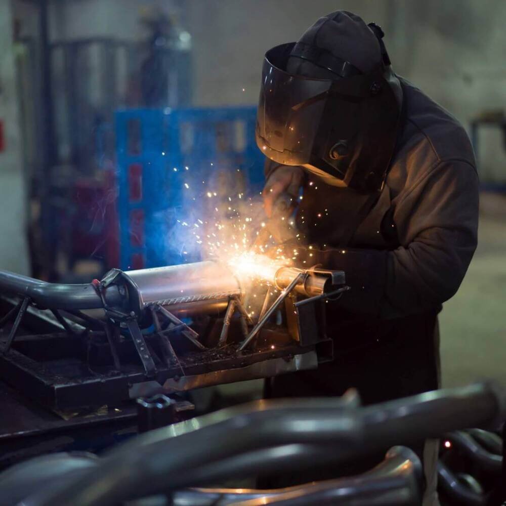 worker-welding-exhaust-pipes-pieces-together-1.jpg